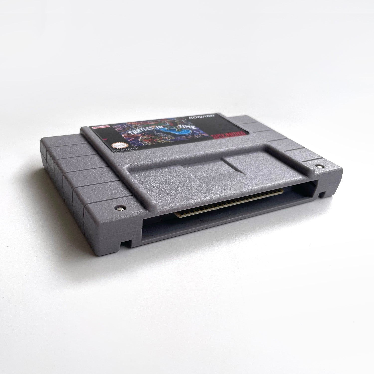 Bottom angled view of Teenage Mutant Ninja Turtles IV: Turtles in Time SNES cartridge.